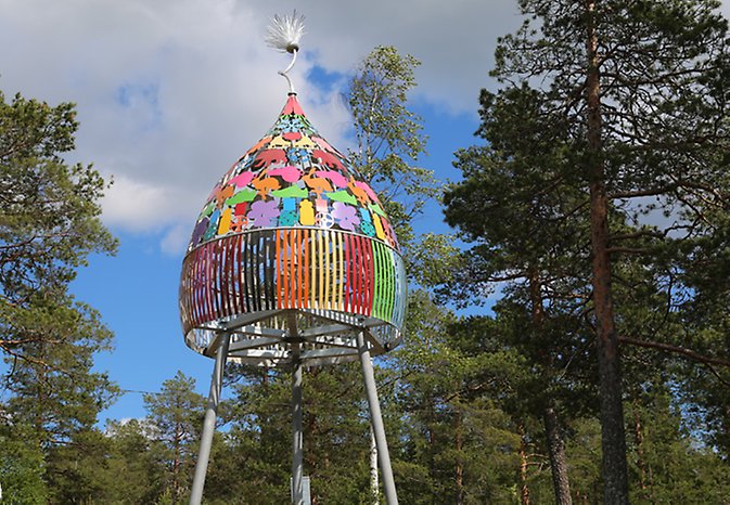 Tio meter högt konstverk i metall föreställer färgglad toppluva med tofs