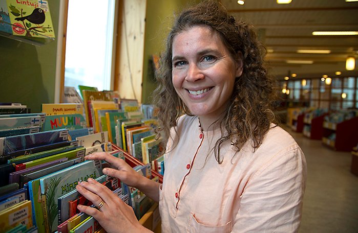 Anna-Maria Weman bläddrar i lådorna med finskspråkiga barnböcker på Arkenbiblioteket.