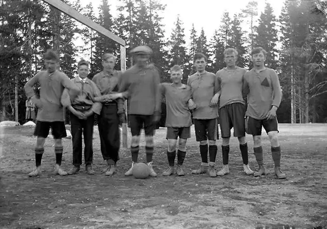 Svartvitt fotografi på åtta pojkar i rad iklädda fotbollskläder.