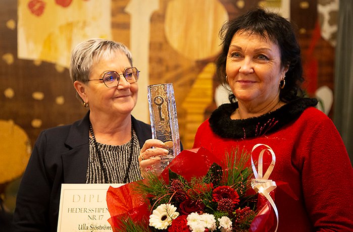 Eva Sonidsson, kultur och fritidsnämndens ordförande,  delar ut blommor och glasskulpturen stadens nyckel till Ulla Sjöström, Musikmakarna